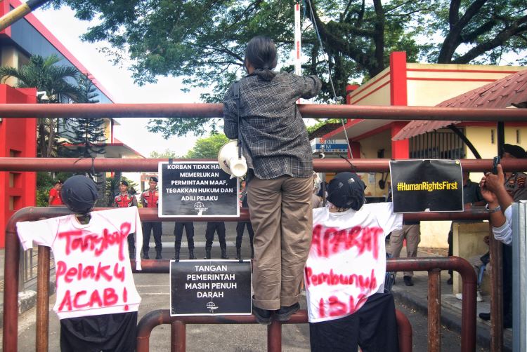 Orator dalam aksi Kamisan Medan memanjat pagar Kantor Kepolisian Daerah Sumatera Utara saat berorasi