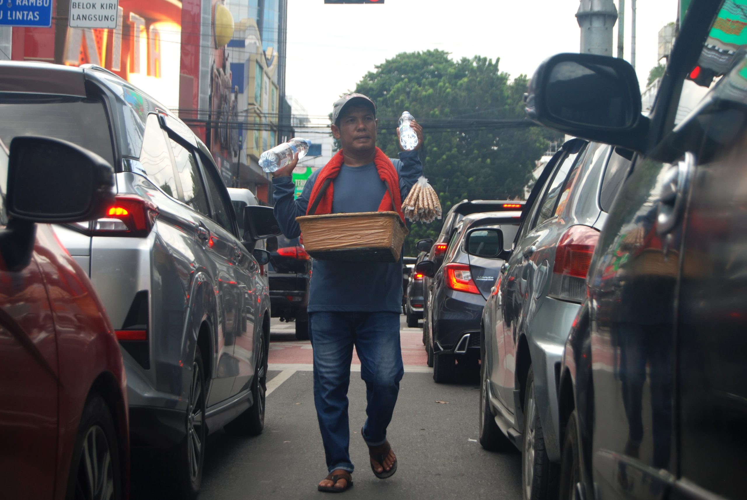 Pedagang rokok asongan Doli menjajakan rokok di sela-sela mobil yang menunggu lampu merah Jalan Brigjen Katamso, Medan