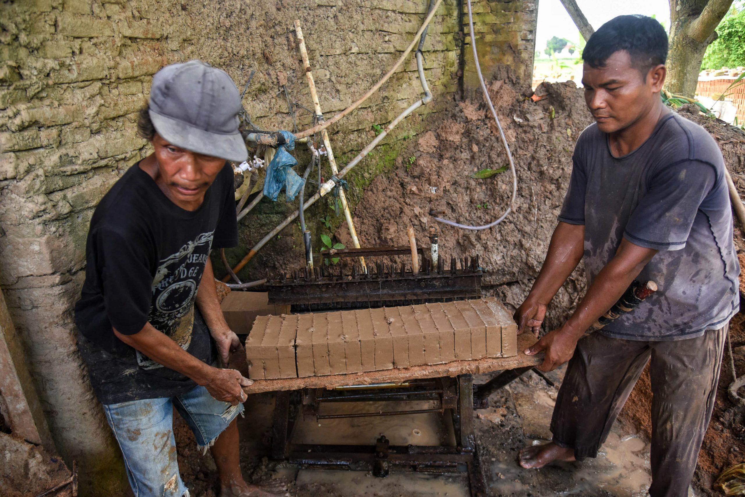 Para perajin mengangkat batu bata yang baru dipotong di Pakam, Deli Serdang, Sumatera Utara