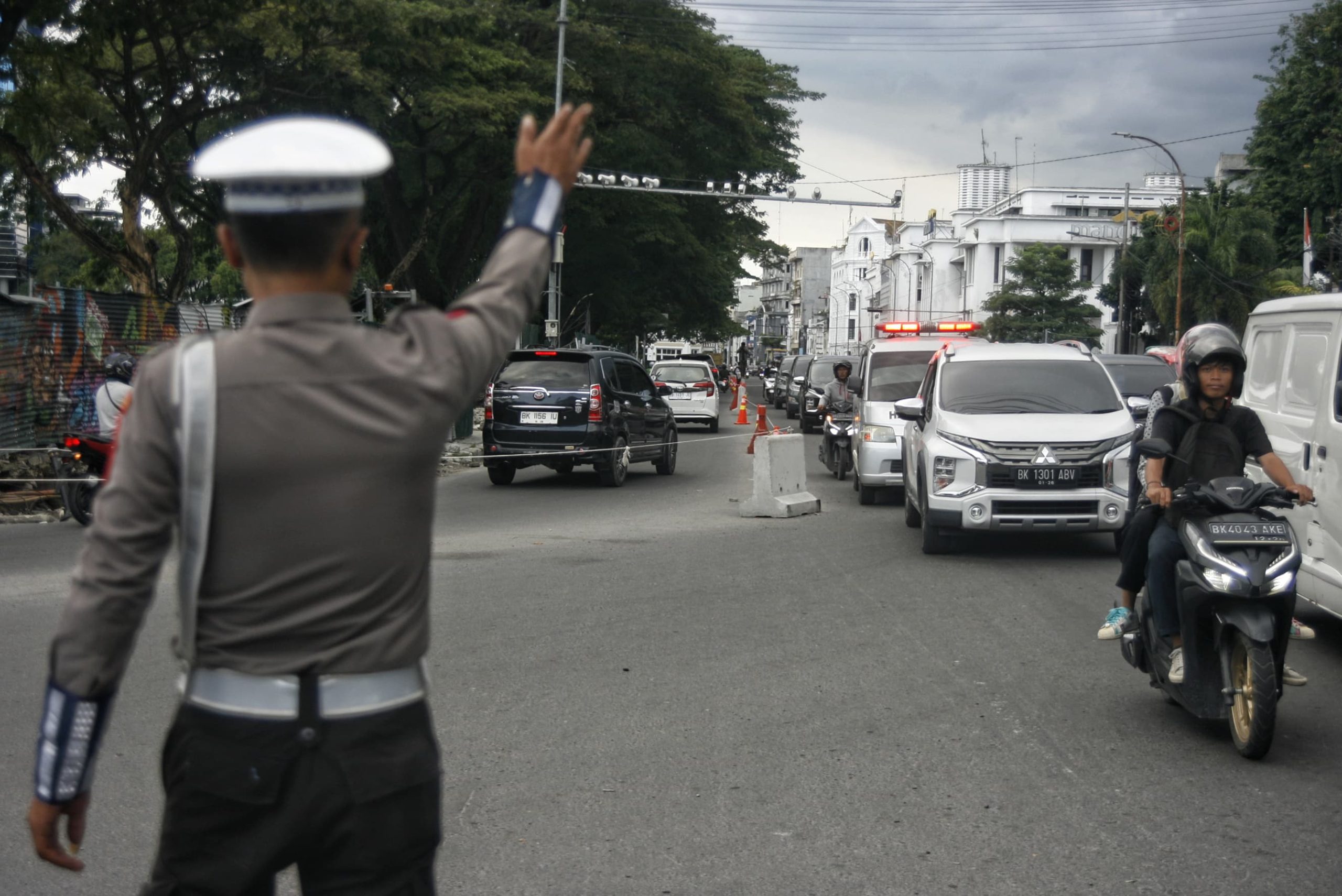 Seorang petugas kepolisian mengarahkan pengendara saat melintas di kawasan Jalan Balai Kota, Medan